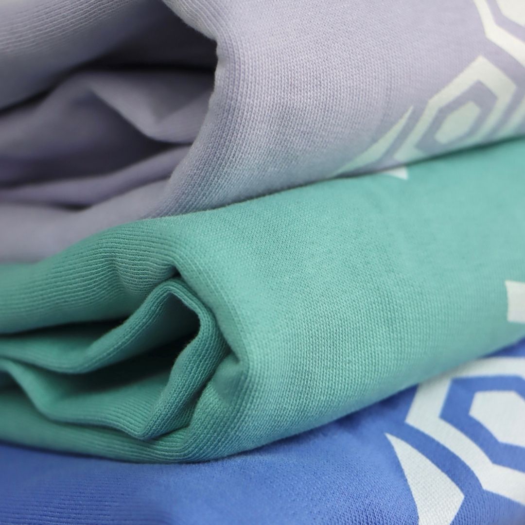 organic sweatshirts in lavender, teal and bright blue, folded, showing quality finish